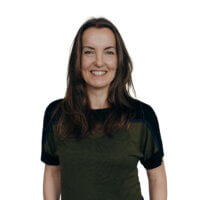 Portrait of Dr. Sandra Gärtner, co-founder of GreenAdz and mediaresearch42, smiling warmly in a professional yet approachable setting. She has long brown hair, wears a black and olive green top, and is positioned against a clean white background. Dr. Gärtner specializes in sustainable market research, influencer marketing, and responsible AI initiatives like Trees4AI.